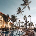Photo by Christian Lambert brown wooden lounge chairs near pool surrounded by palm trees